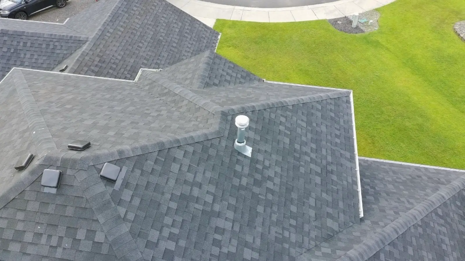 New charcoal shingle hip roof with ridge vents and roof vents